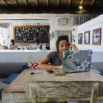 A remote worker with a laptop at a cafe overlooking a scenic view
