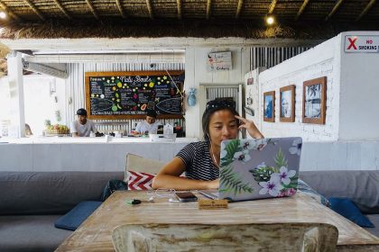 A remote worker with a laptop at a cafe overlooking a scenic view