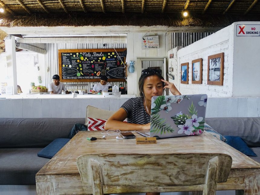 A remote worker with a laptop at a cafe overlooking a scenic view