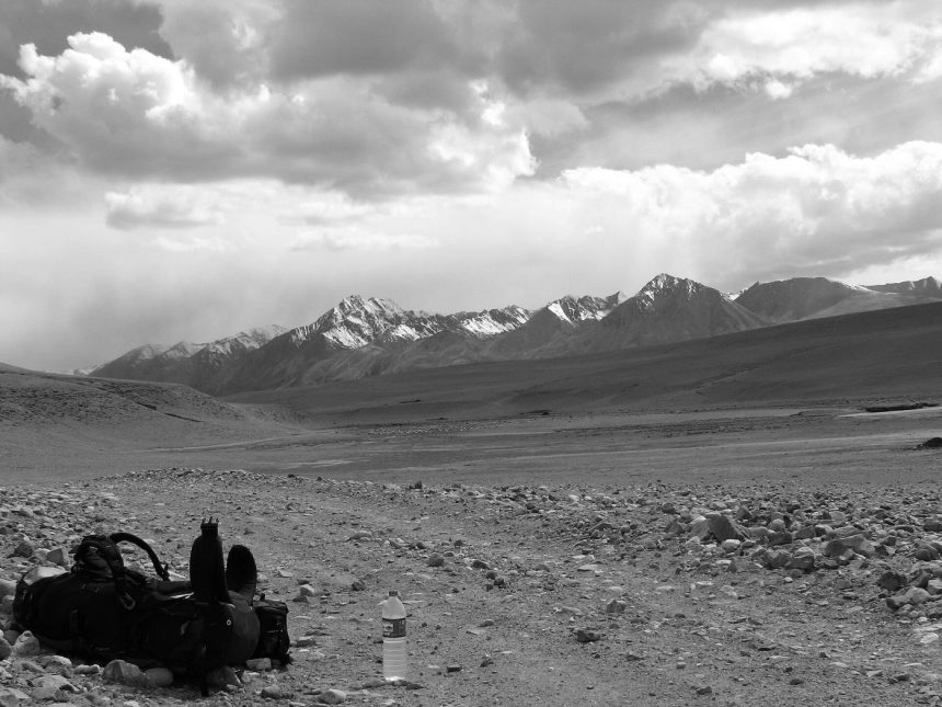 A traveller with a backpack walking a mountain road